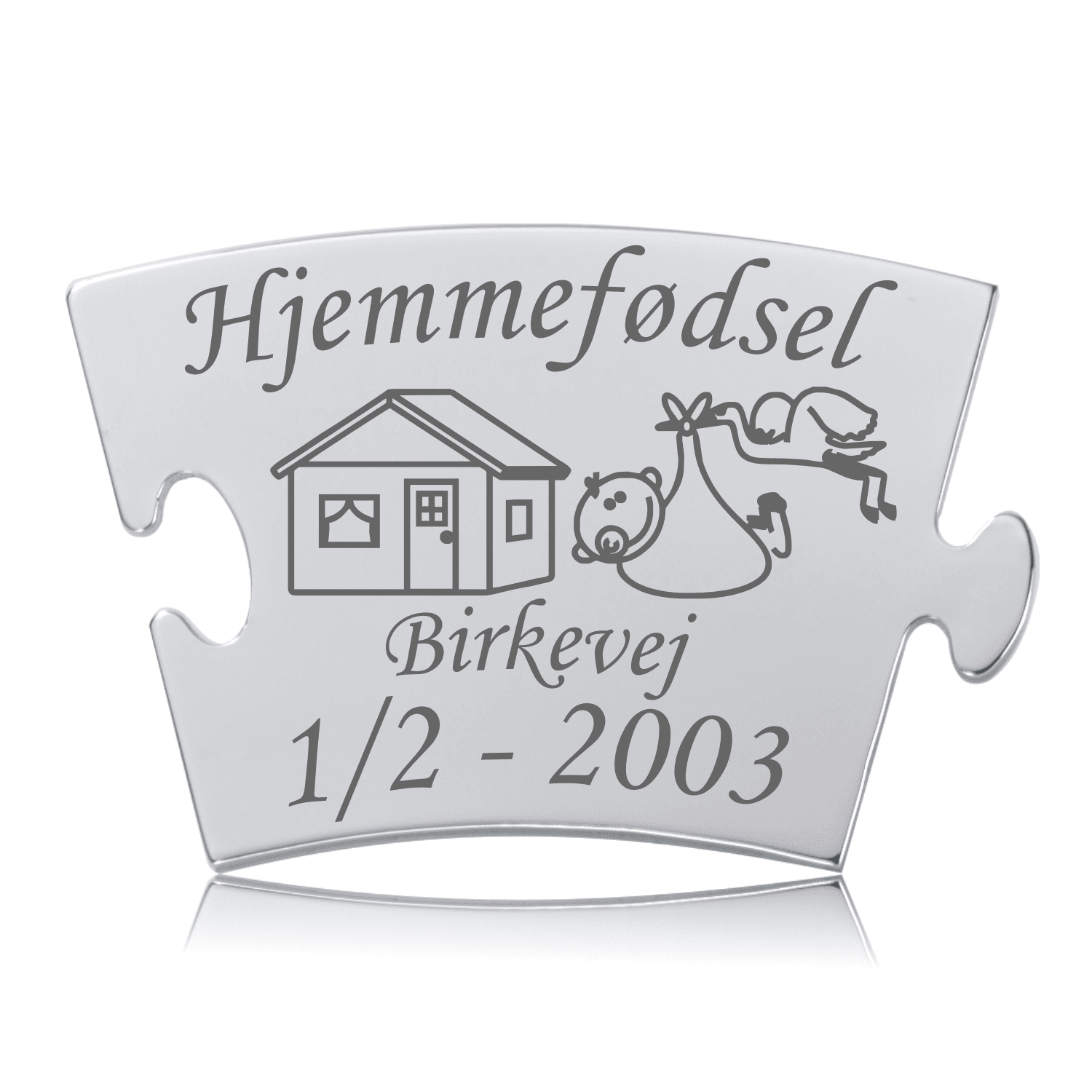 Memozz Classic mindebrik med teksten "Hjemmefødsel", et hus og en stork, udført i mørk lasergravering på skinnende rustfrit stål.