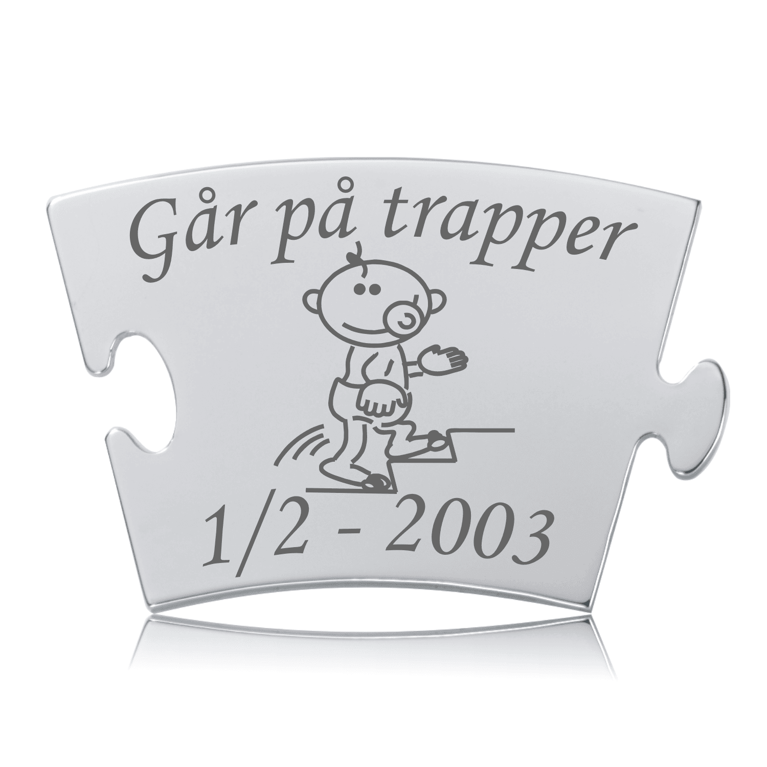 Memozz Classic mindebrik i sølvfarvet rustfrit stål med gravering af teksten "Går på trapper" og en tegning af en glad baby, der klatrer op ad en trappe. Graveringen er mørkegrå.