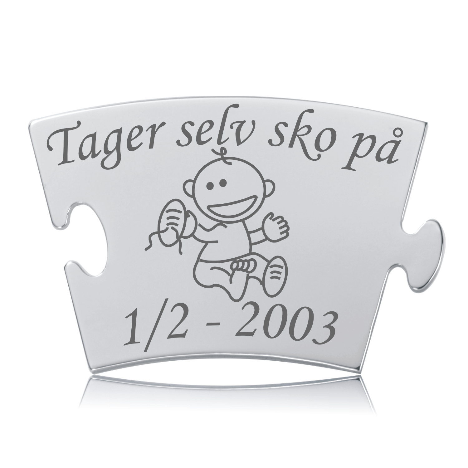 Memozz Classic brik i håndpoleret rustfri stål med gravering af et barn der tager sko på, og teksten "Tager selv sko på".