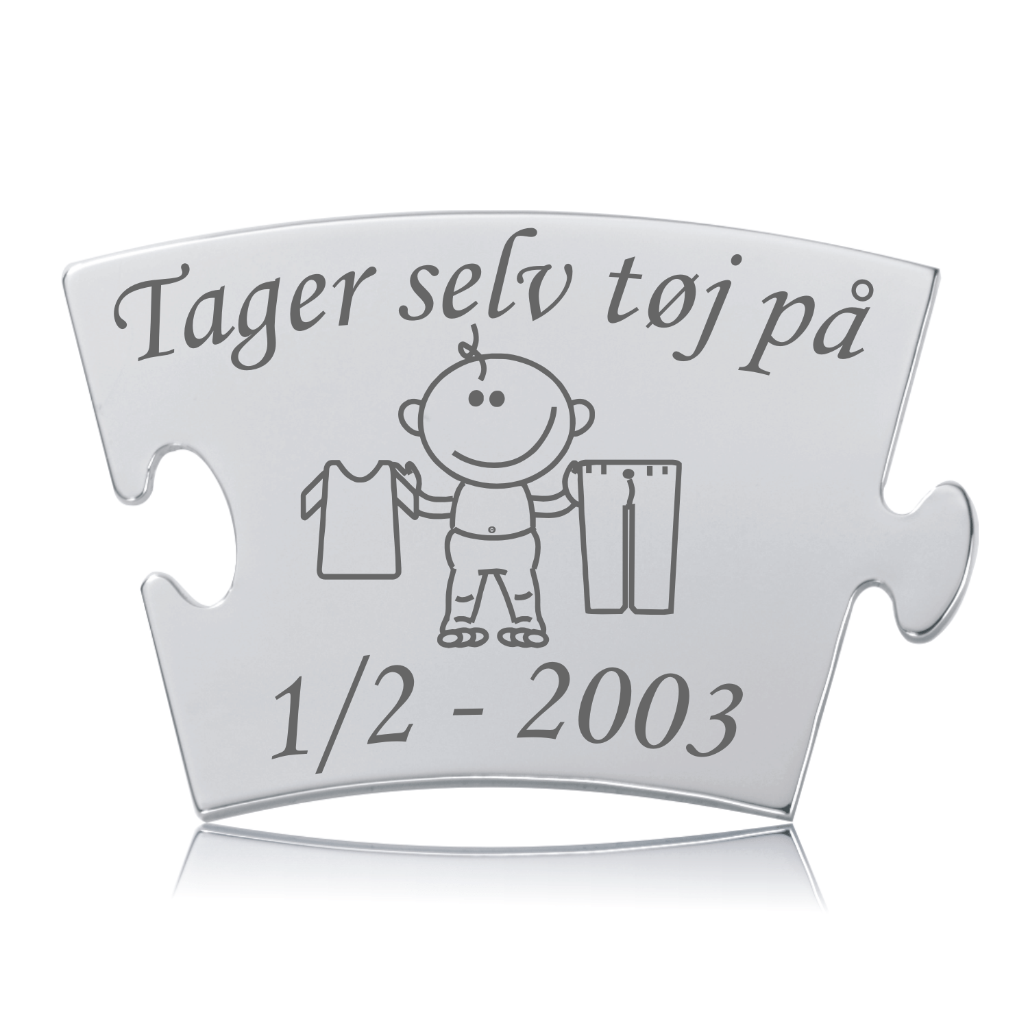 Memozz Classic brik i blankt, rustfrit stål med teksten "Tager selv tøj på" og et illustreret barn, der holder tøj, graveret i mørkegrå