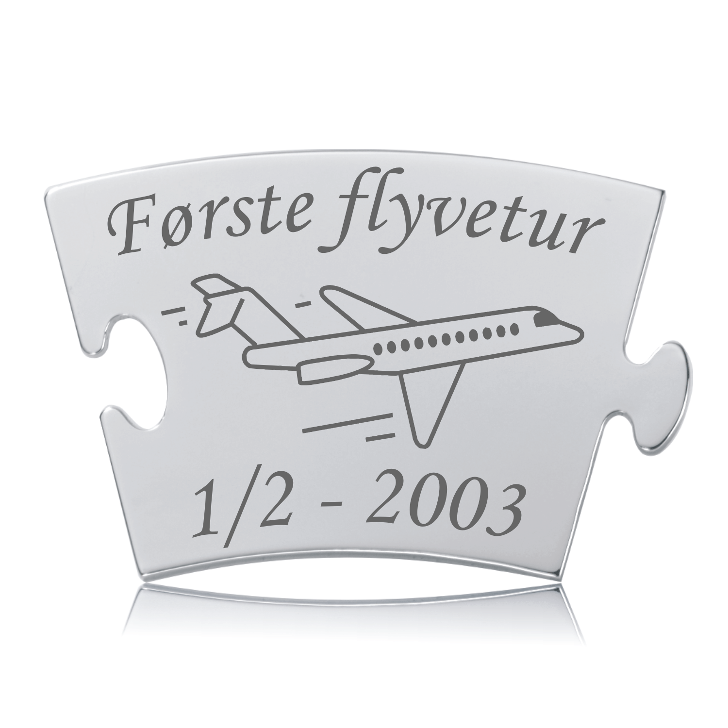 Blank, skinnende Memozz Classic brik med teksten "Første flyvetur" og et stregtegnet fly i mørkegrå gravering.