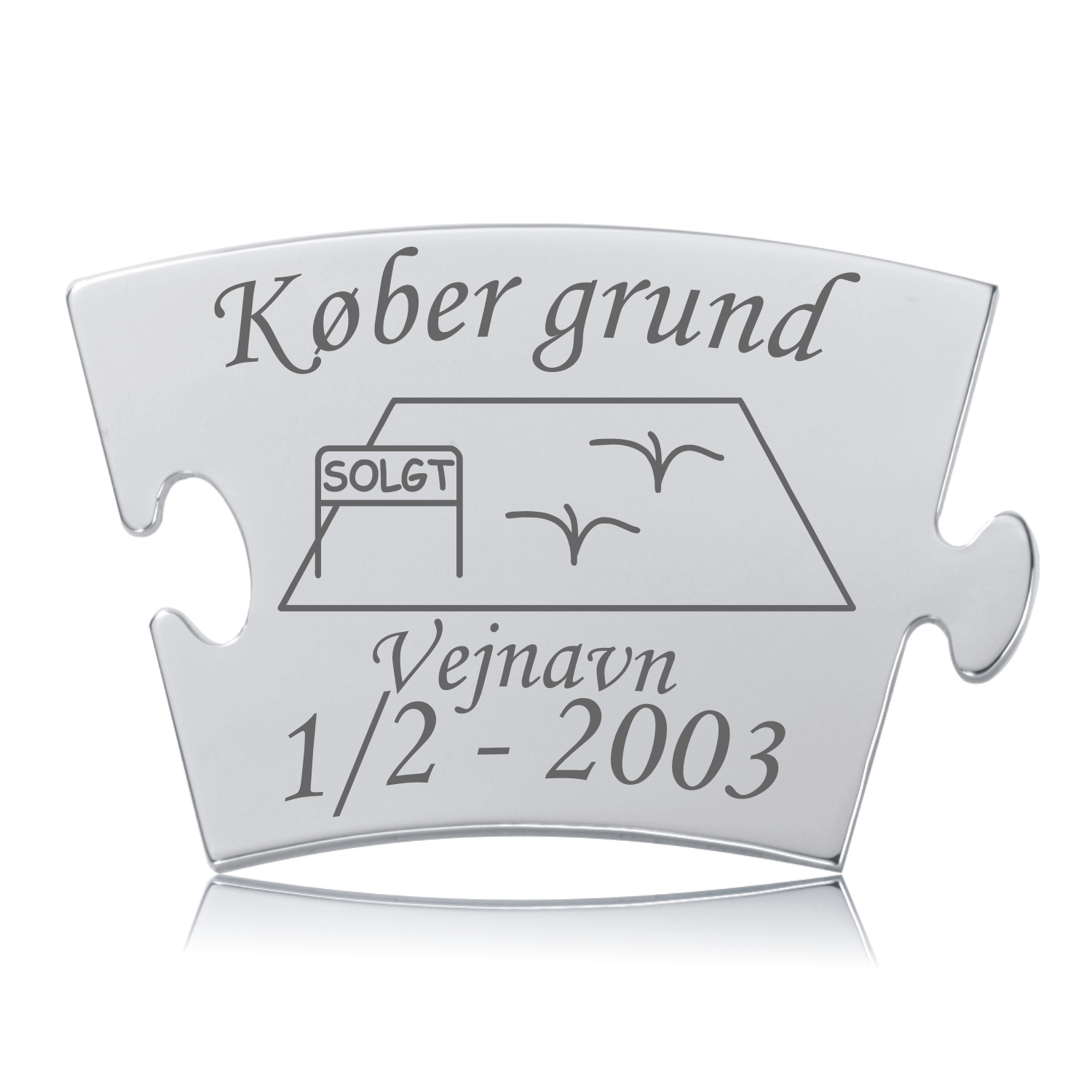 Memozz Classic brik "Køber grund" i håndpoleret rustfrit stål med mørk lasergravering, der viser et hus, "SOLGT" skilt og fugle, samt "Vejnavn" og dato.