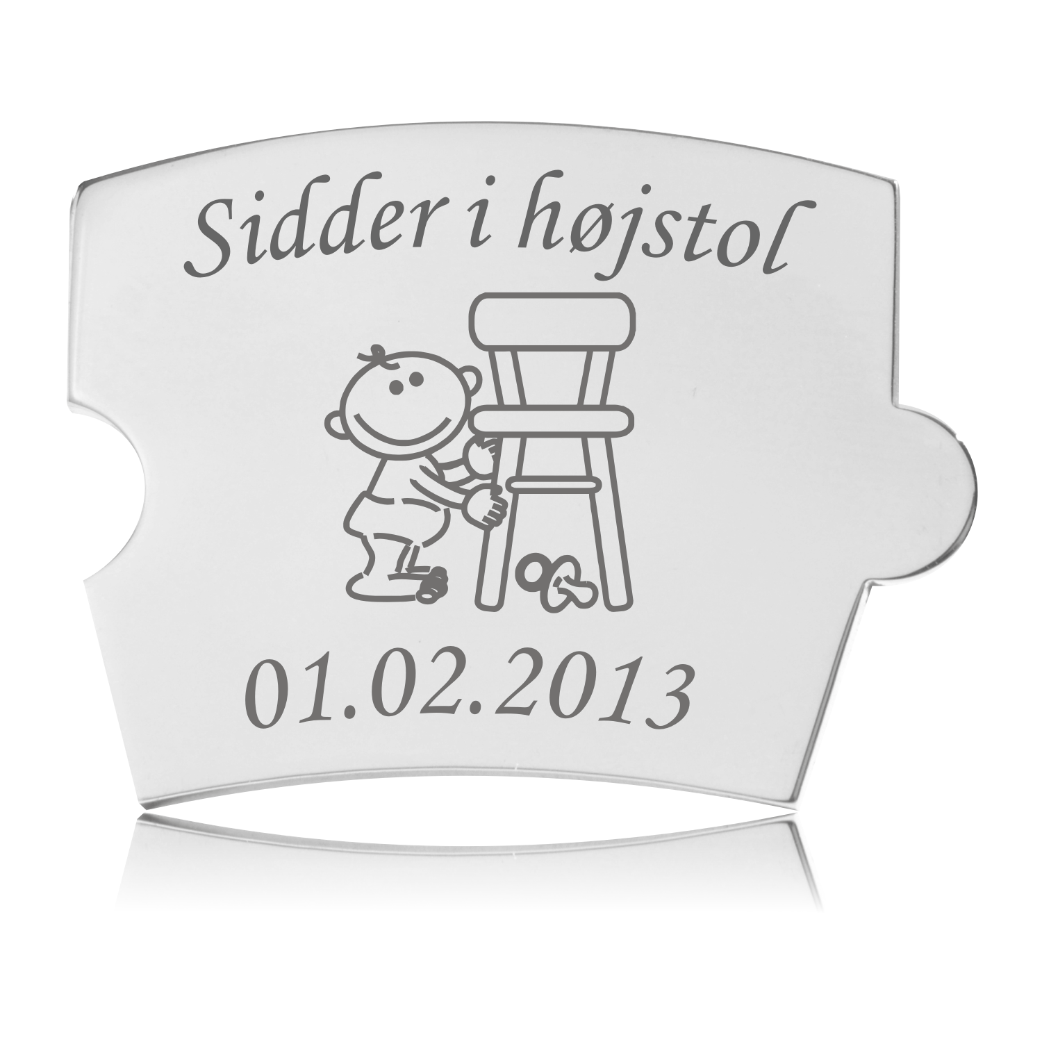 Memozz Spin mindebrik 'Sidder i højstol' i poleret stål med gravering af en baby ved en højstol og plads til dato.