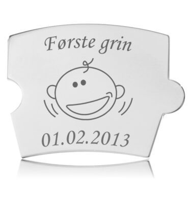 Memozz Spin brik "Første grin" i blankt, håndpoleret rustfrit stål med graveret babyansigt og inskription.
