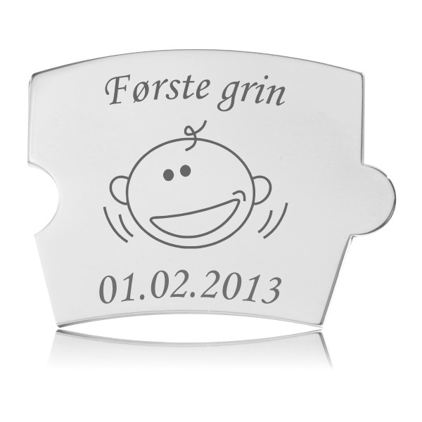 Memozz Spin brik "Første grin" i blankt, håndpoleret rustfrit stål med graveret babyansigt og inskription.