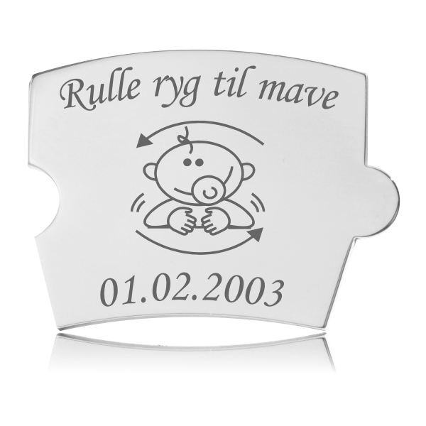 Memozz Spin brik i poleret rustfrit stål med gravering af et barn der ruller fra ryg til mave og "Rulle ryg til mave" tekst.
