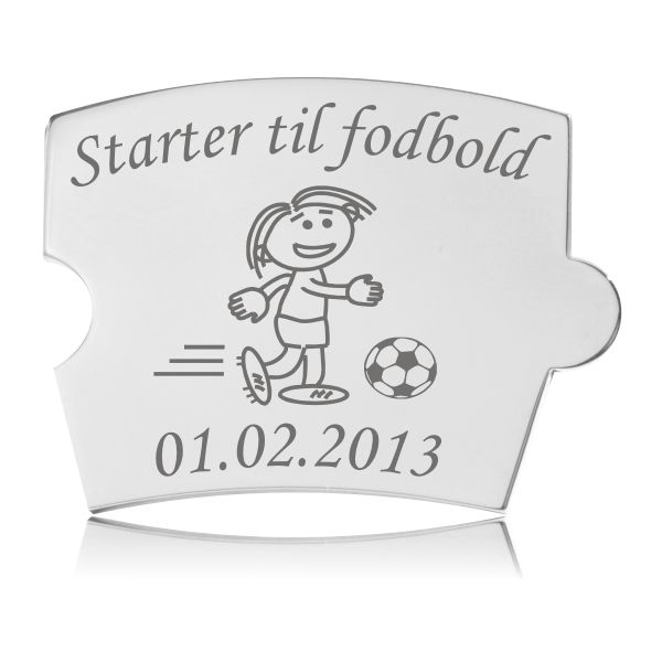 Memozz Spin brik i poleret rustfrit stål med gravering af en pige, der spiller fodbold, og teksten "Starter til fodbold".