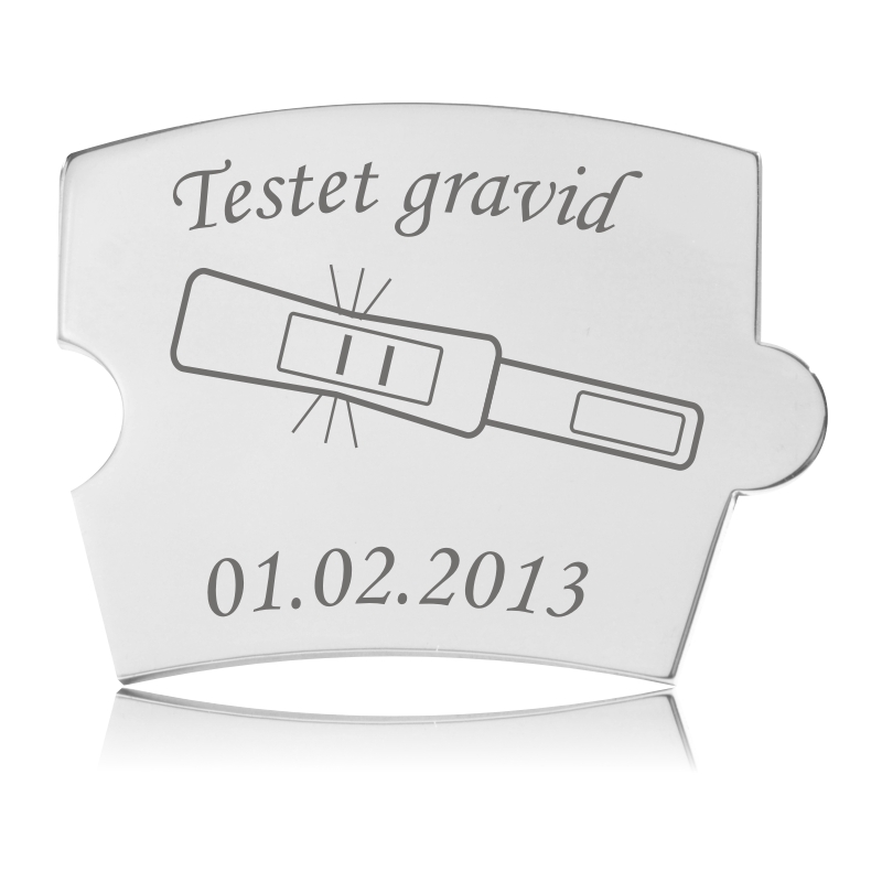 Memozz Spin brik "Testet Gravid" i håndpoleret rustfrit stål med gravering af graviditetstest og tekst.