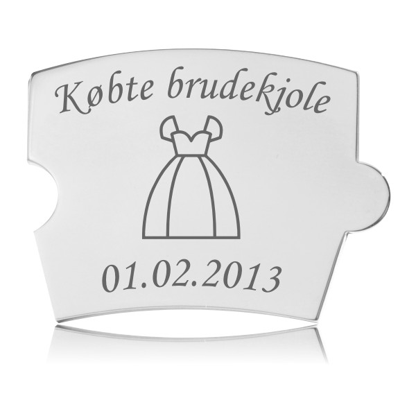 Memozz Spin brik i poleret rustfrit stål med gravering af brudekjole og teksten "Købte brudekjole" samt en dato. Lys baggrund.