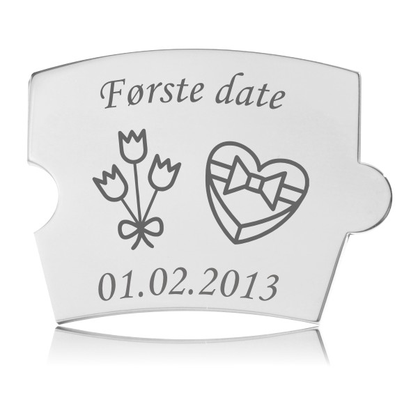 Blank, rektangulær Memozz Spin brik i poleret rustfrit stål med afrundede hjørner. Graveret med teksten "Første date", en buket blomster og en hjerteformet æske.