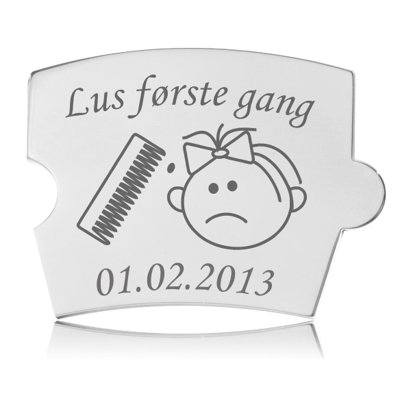 Memozz Spin brik i håndpoleret rustfrit stål med gravering "Lus første gang" og illustration af en lusekam og ked af det ansigt. Datoen 01.02.2013 er også synlig.