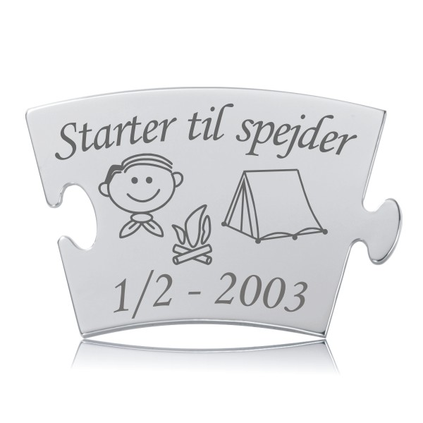 Starter til spejder - dreng brik til Memozz Classic Memozz Classic brik foreviger en drengs spejderstart med indgraveret tekst, en dreng, lejrbål og telt illustration. Den blanke overflade reflekterer et varmt lys.