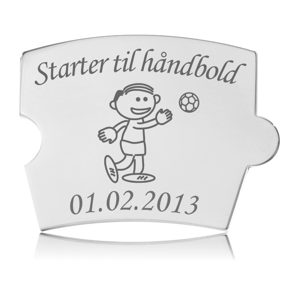 Memozz Spin brik i håndpoleret rustfrit stål, graveret med en tegning af en glad dreng der kaster en håndbold og teksten "Starter til håndbold"